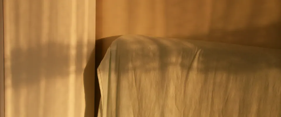 Empty bed with warm morning light and soft shadows